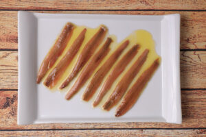 Portion of anchovies from Santoña in white rectangular plate on wooden table