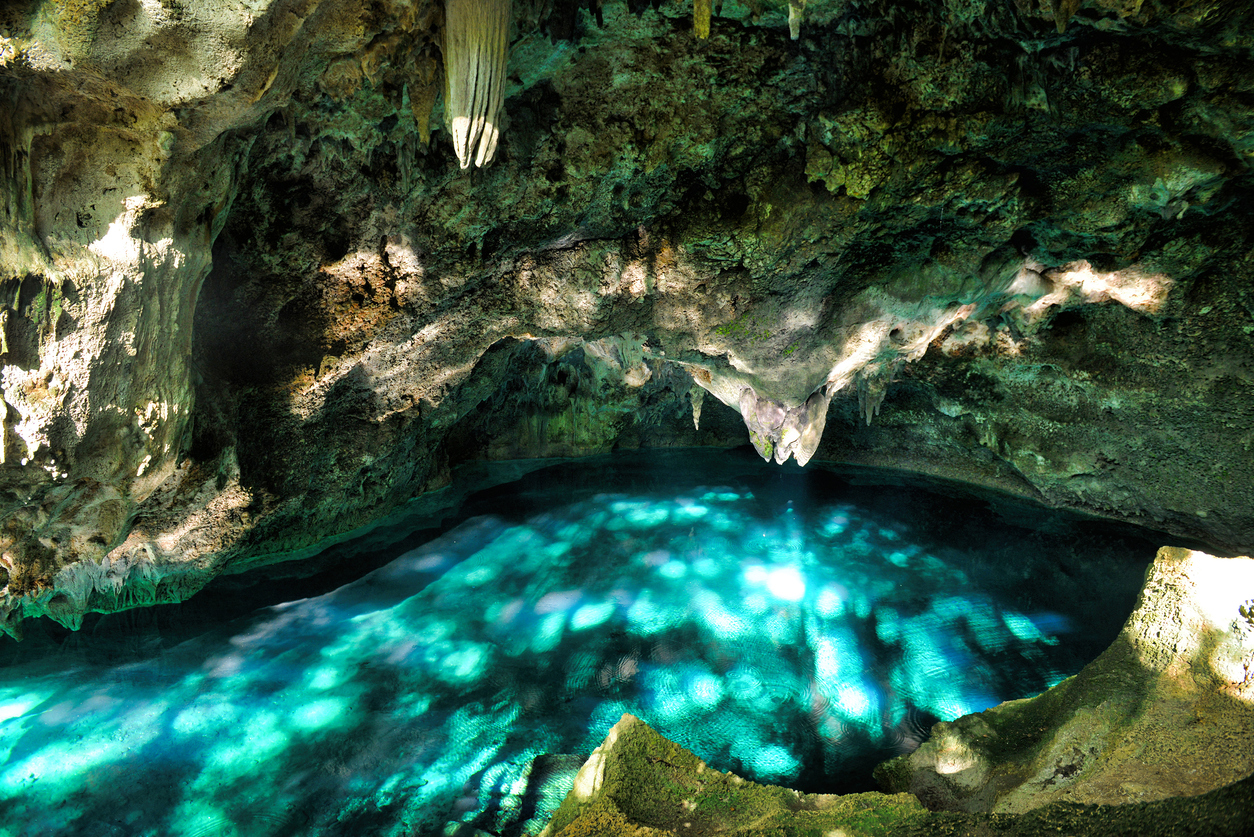 Mystery misty cave in the jungle, with sun rays over the turquoise and blue underground lake water. Lake Azufre. The 3 Eyes National Park (Los Tres Ojos) in Santo Domingo, Caribbean, Dominican Republic