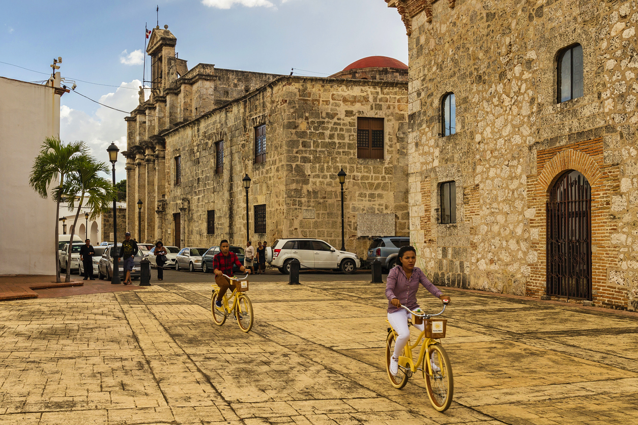 SANTO DOMINGO - DOMINICAN REPUBLIC - December 25, 2016: Street view of the National Pantheon with Calle Las Damas the oldest and best preserved old town street when tourists pass by with bicycles.