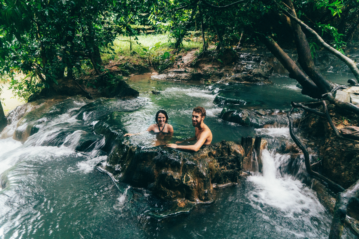 Young Caucasian couple bathing in hot spring waterfall in Thailand