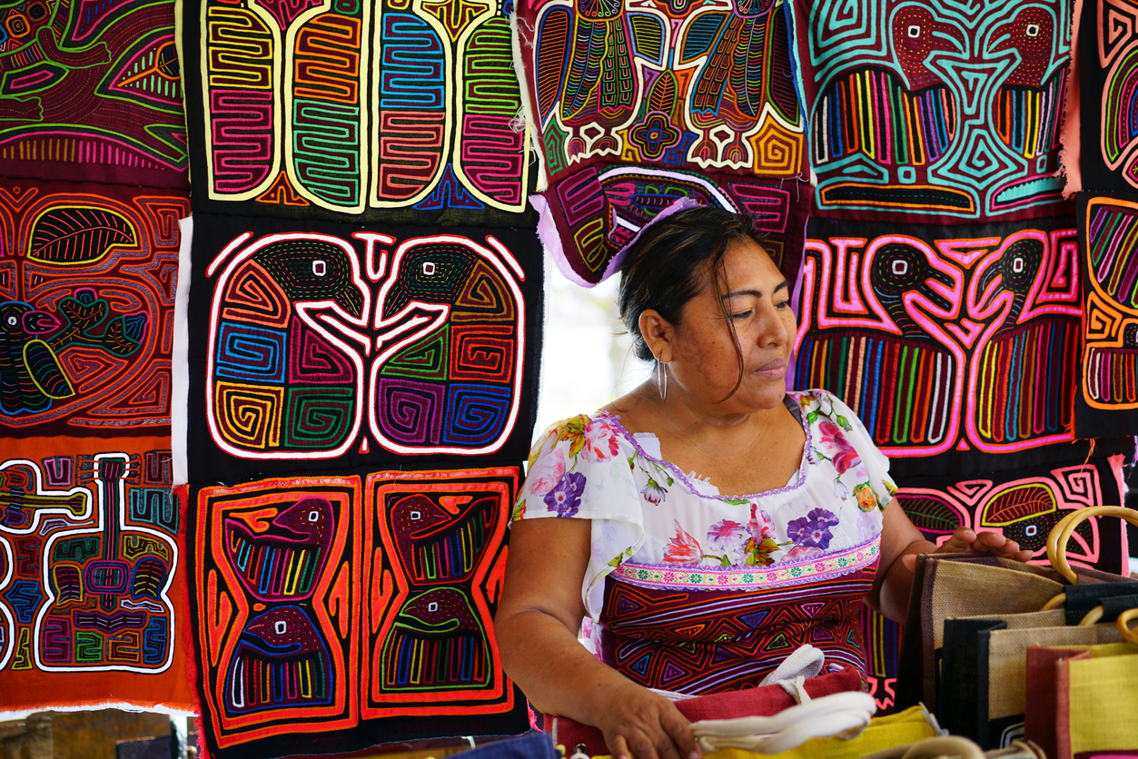 Panama City, Panama - February 12, 2017: Kuna Yala woman in very traditionally colorful clothes selling souvenirs from her kiosks, mostly for tourists. The kiosk is in Casco Viejo an old part of Panama City. Kuna Yala tribe belongs to indigenous people living on san Blas islands and their handcraft is most famous in Panama.